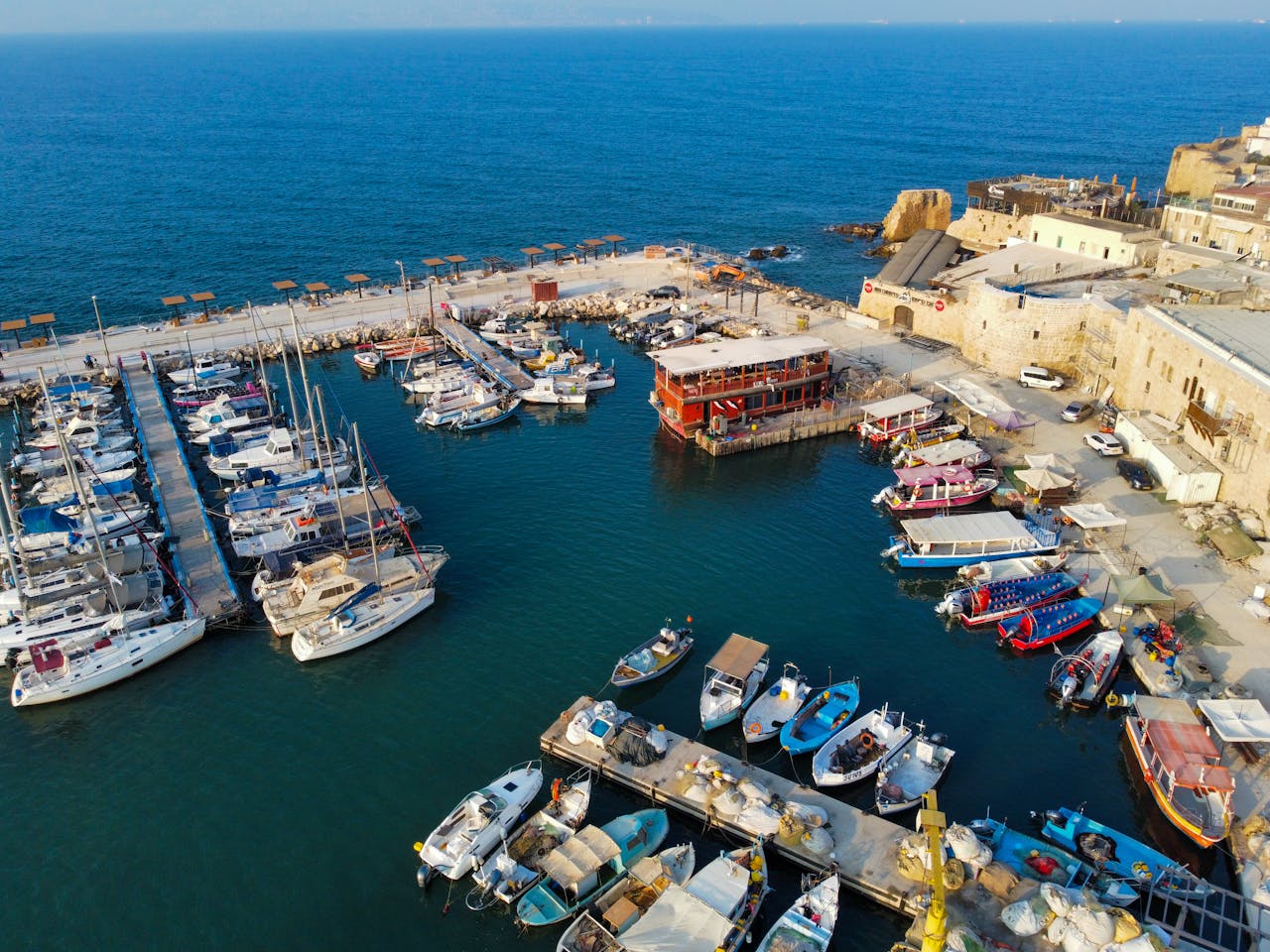 Stunning aerial view of Acre marina showcasing docked boats and historic buildings in Israel.