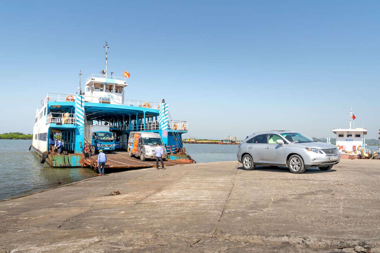 Ferry loaded with vehicles docked at a sunlit harbor, showcasing transportation and travel.